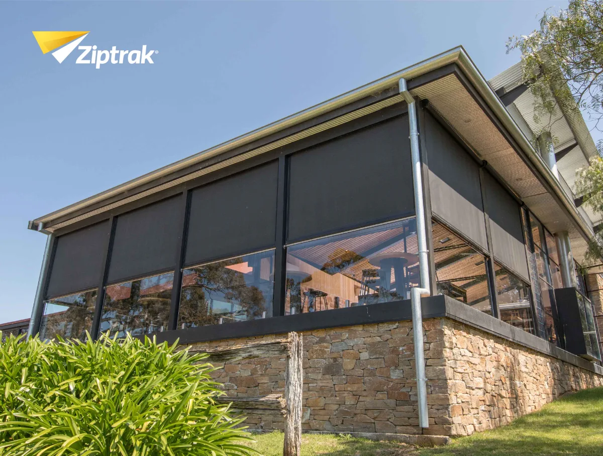 Covered Melbourne patio at dusk with Ziptrak outdoor blinds half lowered and warm interior light.