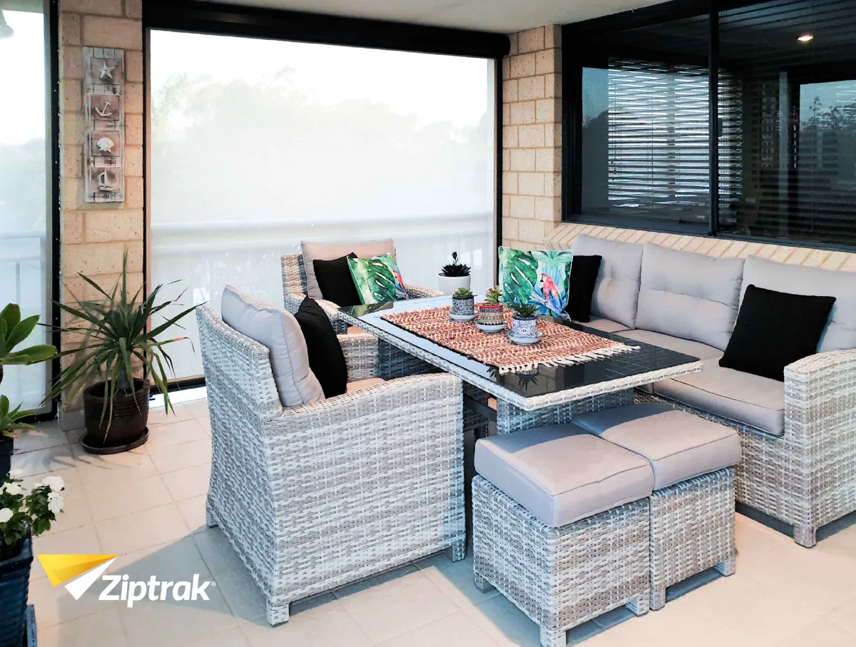 Family enjoying a long lunch under a covered patio with Ziptrak blinds lowered against the wind.